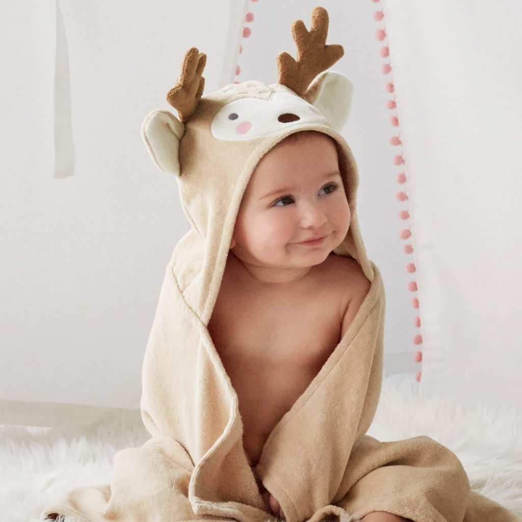 A child pretend playing in their deer hooded bath towel, made by Elegant Baby