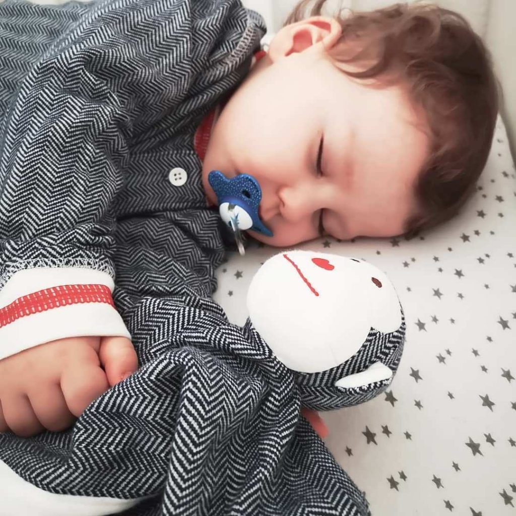 A baby sleeping with the Juddlies monkey organic cotton security blanket