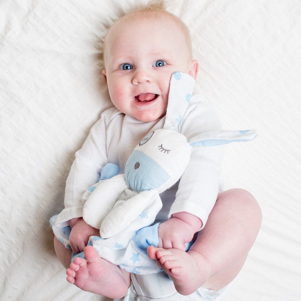 An adorable combination of a cute boy snuggling with the Lulujo blue puppy lovie security blanket for babies